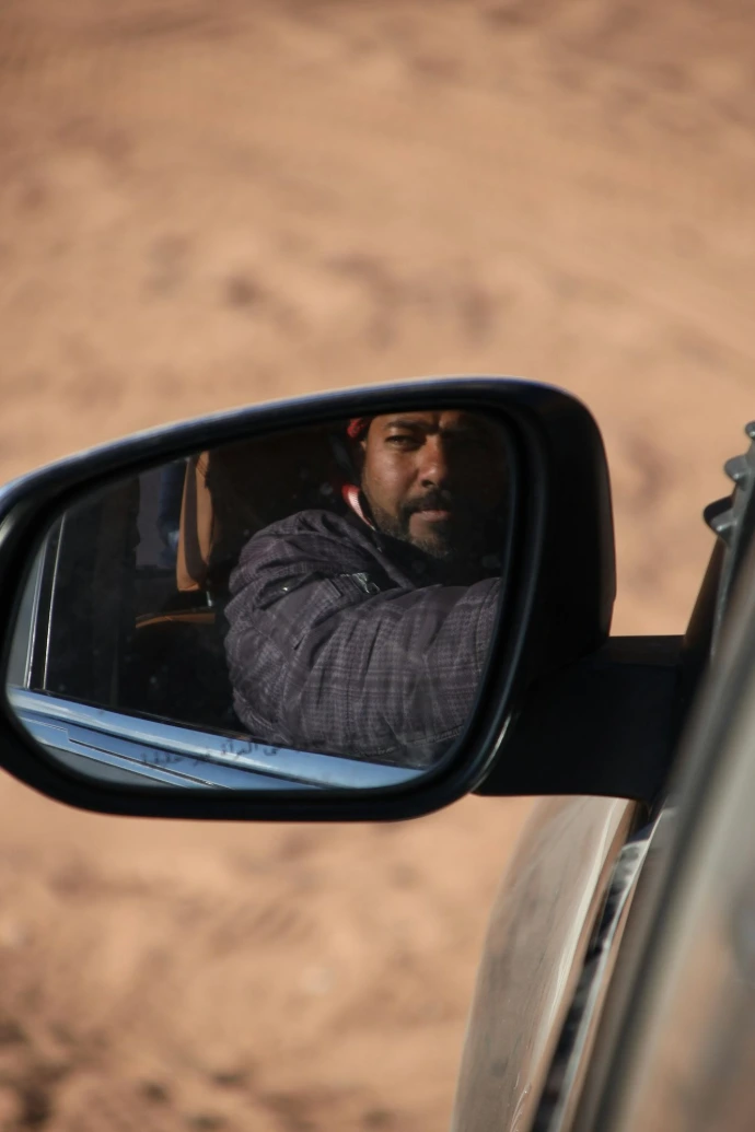 Man's reflection in a car side mirror